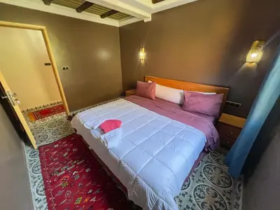 a bedroom with a large bed with pink pillows at Tabourihte Gardens in Tinerhir