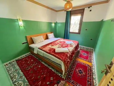 a bedroom with a bed with green walls and red carpet at Tabourihte Gardens in Tinerhir