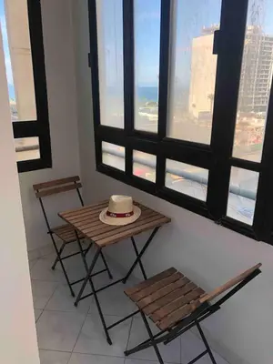 a table with a hat on it in a room with windows at Bel appartement in Oulad Akkou