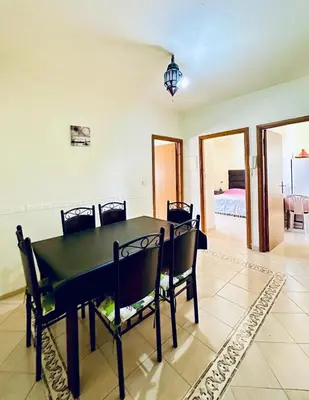 a dining room with a black table and chairs at Hay mohamedi in Oulad Akkou