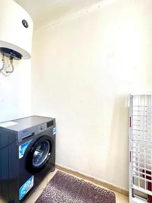 a washing machine in a laundry room with a lamp at Hay mohamedi in Oulad Akkou