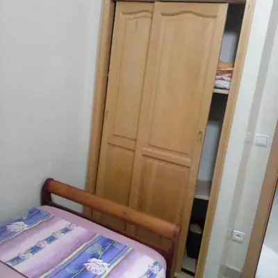a closet with a wooden door next to a bed at Secure Beachfront Apartment Near Hilton Golf & Spa in Oulad Akkou