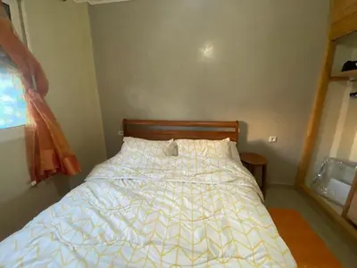 a bedroom with a bed with a white comforter at Secure Beachfront Apartment Near Hilton Golf & Spa in Oulad Akkou