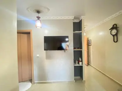 a living room with a tv on a wall at Secure Beachfront Apartment Near Hilton Golf & Spa in Oulad Akkou
