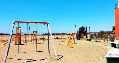 an empty playground with swings in the sand at Secure Beachfront Apartment Near Hilton Golf & Spa in Oulad Akkou