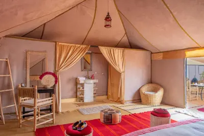 a bedroom in a tent with a table and a desk at Sanmao Desert Luxury Camp in Merzouga
