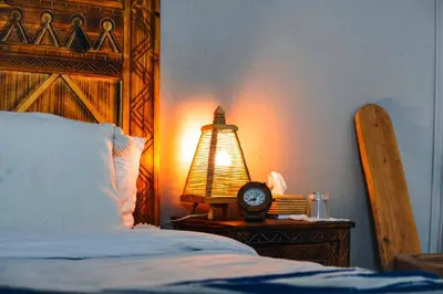 a bed with a lamp and a clock on a table at Sanmao Desert Luxury Camp in Merzouga