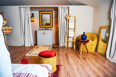 a bedroom with wicker chairs and a room with wooden floors at Sanmao Desert Luxury Camp in Merzouga