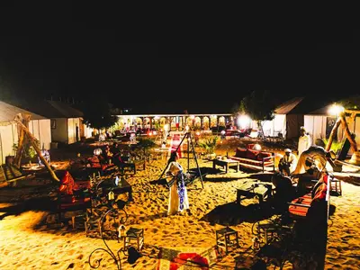 a group of people on a beach at night at Sanmao Desert Luxury Camp in Merzouga