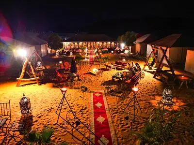 a group of people sitting on a beach at night at Sanmao Desert Luxury Camp in Merzouga
