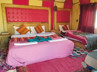 two beds in a hotel room with pink at hiya luxury camp in Merzouga
