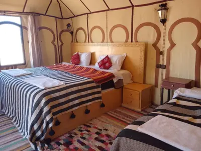 a bedroom with a bed with a striped comforter at hiya luxury camp in Merzouga