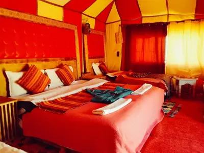 a bedroom with two beds with red sheets at hiya luxury camp in Merzouga