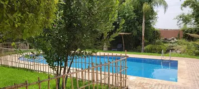 a swimming pool in a yard with a fence around it at طريق تمصلوحت مراكش in Oulad Akkou