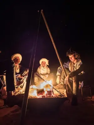 a group of people sitting around a fire at Glamping Under Stars in Merzouga