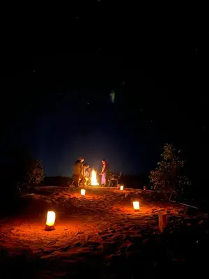a group of people sitting around a fire at night at Glamping Under Stars in Merzouga