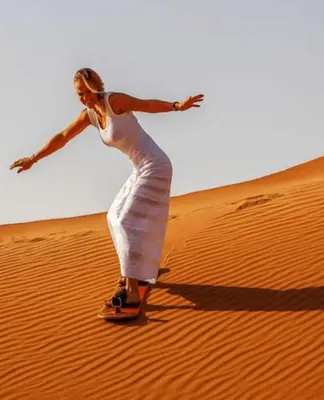 a woman in a white dress riding on a desert at Glamping Under Stars in Merzouga