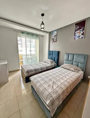 two beds in a bedroom with blue furniture at Ismail in Oulad Akkou