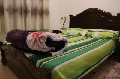 an unmade bed with a green and white blanket on it at Appartement juste pour les familles in Ifrane