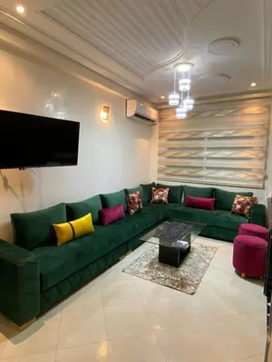a living room with a green couch and a flat screen tv at Family Apartment in City Centre in Douar Oulad Mhammed