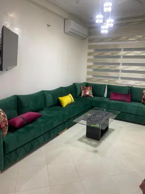 a green couch with colorful pillows in a living room at Family Apartment in City Centre in Douar Oulad Mhammed