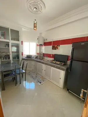 a kitchen with a table and a black refrigerator at Family Apartment in City Centre in Douar Oulad Mhammed