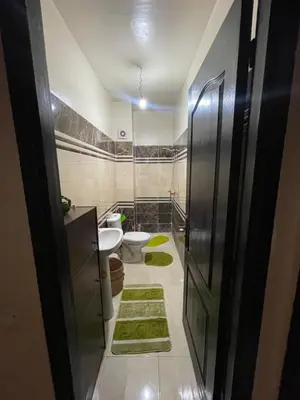 a bathroom with a toilet and two green rugs at Rayhana in Oulad Akkou