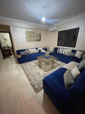 a living room with a blue couch and a table at Rayhana in Oulad Akkou