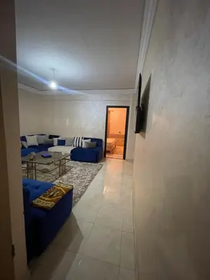 a living room with a blue couch and a table at Rayhana in Oulad Akkou