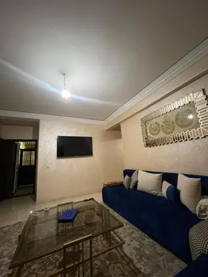 a living room with a blue couch and a glass table at Rayhana in Oulad Akkou