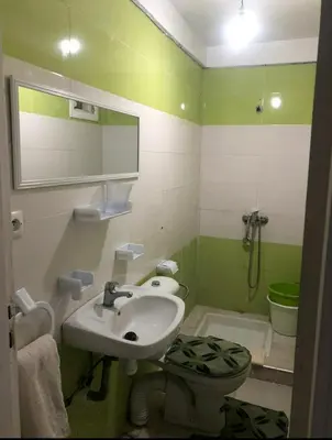 a green and white bathroom with a sink and a toilet at Marhaba in Fès