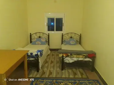 a small room with two beds and a table at Rani hani chez ali in Tinerhir