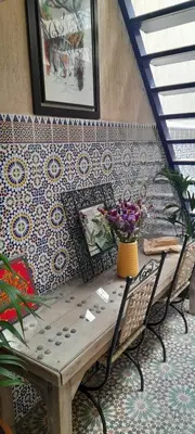 a table and two chairs with flowers on a wall at Riad Kouira in Oulad Akkou