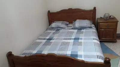 a bed with a blue and white checkered blanket at Chez Faouzia in Taza