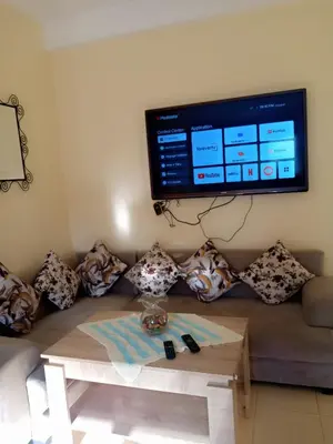 a living room with a couch with a tv on the wall at Saloumi Appartment in Ifrane
