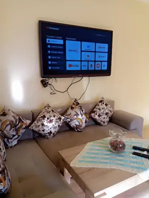 a tv on the wall above a couch with pillows at Saloumi Appartment in Ifrane