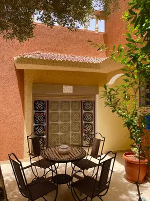 a patio with a table and chairs in front of a building at Dyafat Abla in Oulad Akkou