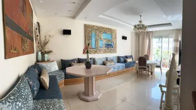 a living room with a blue couch and a table at Appartement avec piscine in Oulad Akkou