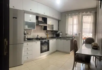 a kitchen with white cabinets and a table in it at Appartement avec piscine in Oulad Akkou