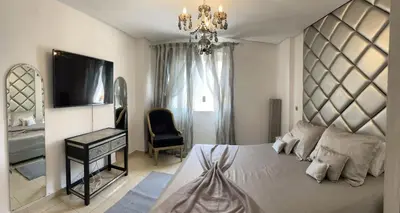 a bedroom with a large bed and a chandelier at Appartement avec piscine in Oulad Akkou