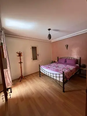 a bedroom with a bed and a wooden floor at appartement amine in Oulad Akkou