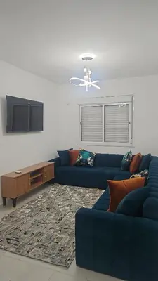 a living room with a blue couch and a tv at MBS imo in Oulad Akkou