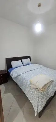 a bedroom with a bed with blue sheets and a light at MBS imo in Oulad Akkou