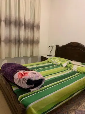 an unmade bed with green and purple sheets on it at Les jardins d'Ifrane in Ifrane