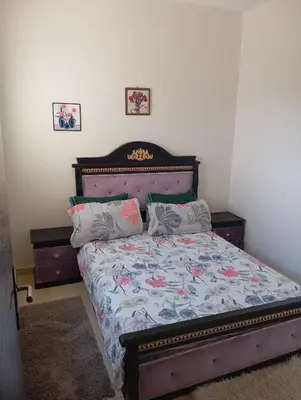 a bedroom with a bed with a wooden headboard at حدائق افران in Oulad Akkou