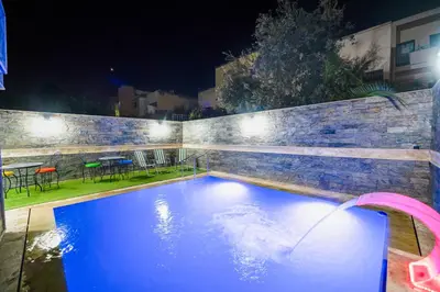 a swimming pool at night with a table and chairs at Riad Les Champs De Fès in Fès