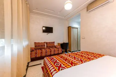 a hotel room with two beds and a television at Riad Les Champs De Fès in Fès
