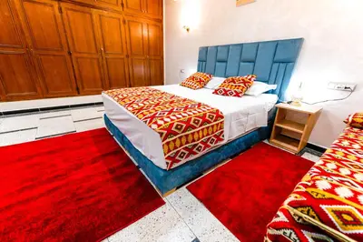 a bedroom with a bed with red and orange pillows at Riad Les Champs De Fès in Fès