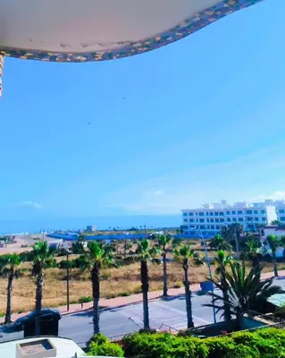 a view of a beach with palm trees and a building at Refined studio with sea view in Oulad Akkou