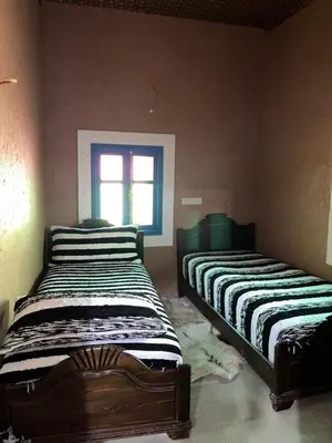 two beds in a room with a window at Auberge Lwalida in Ouled Sguir